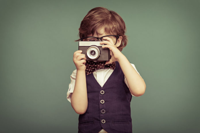 this is an image of a young boy with waistcoat and glasses taking a photo