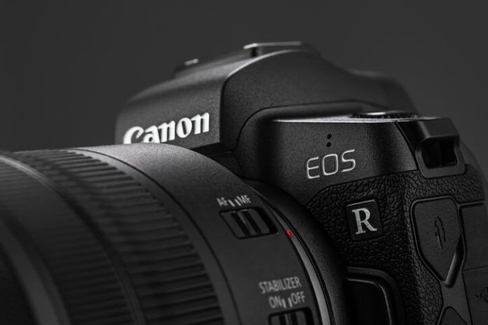 Image of Canon EOS R Mirrorless Digital Camera with Canon EF 24-105mm f4L IS USM lens on a black background. Canon is the world largest SLR camera manufacturer.