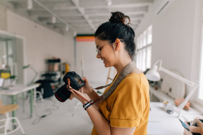 Woman holding a digital camera in her photography studio