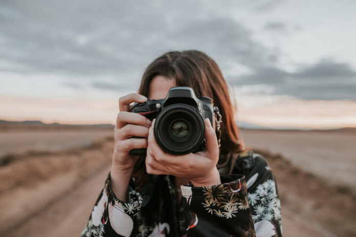 A young woman using a DSLR camera