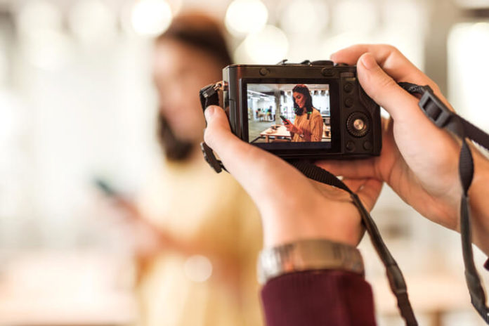 man taking a photo of a young woman using a small digital camera