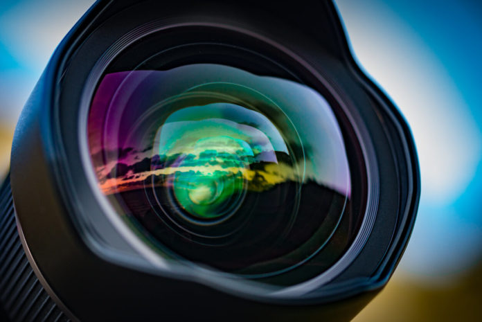 A seascape sunset reflected in the large front element of a 15mm wide angle lens, with the coloured lens element coatings enhancing the effect.